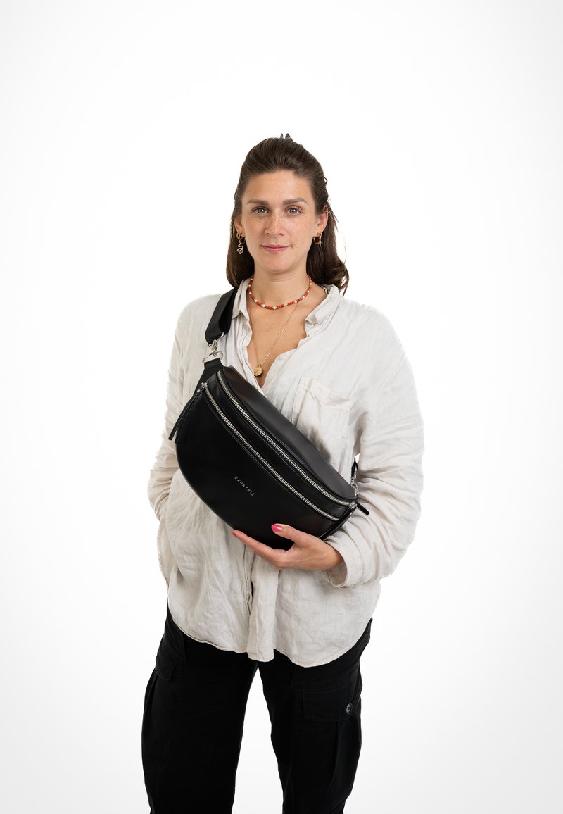 Black leather sling bag with a rounded shape, double zippers, and a sturdy strap. Smooth texture with subtle logo detail on front.