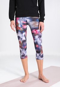 Leggings capri multicolores que presentan una tela suave y elástica con un patrón abstracto difuminado en tonos de rosa, azul y negro.