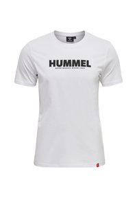 Vit bomullströja med en stor svart "HUMMEL"-logotyp och texten "SPORTSWEAR SINCE 1923". Korta ärmar, rundad halslinning, röd accent-tagg.