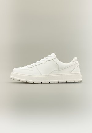Weißer Sneaker mit niedrigem Schaft, strukturierter Sohle, Schnürverschluss und minimalen Steppnähten auf neutralem Hintergrund.