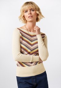 Pullover-Sweater mit beigem Grundton und mehrfarbigem Zickzack-Muster. Lange Ärmel und gerippte Bündchen mit einem schmalen Taillenbund.
