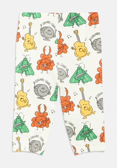 Legingi ar baltu fonu ar karikatūru rakstu, kurā attēloti muzikāli kukaiņi un radības oranžās, zaļās un dzeltenās nokrāsās.