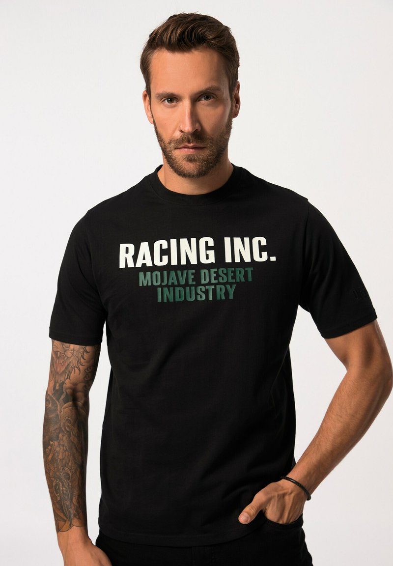 Camiseta negra de algodón, con un texto en blanco y verde audaz que dice "RACING INC. MOJAVE DESERT INDUSTRY" en el frente. Diseño minimalista.