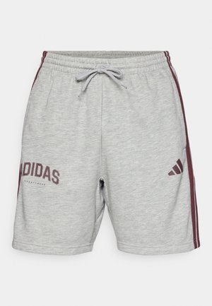 Szürke sportnadrág zsinóros derékkal, bordó oldalcsíkkal és "Adidas" logóval az elején. Puha, pamut keverék anyag.