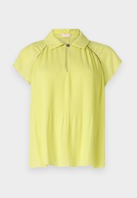 Blusa gialla pallido con un design plissettato, maniche corte, colletto e chiusura con zip frontale. Tessuto morbido con una trama liscia.