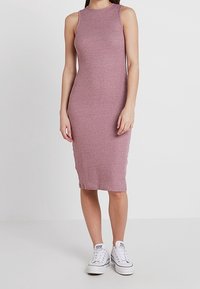 Robe midi sans manches rose côtelée en tissu extensible ; silhouette ajustée ; associée à des baskets blanches pour un contraste.