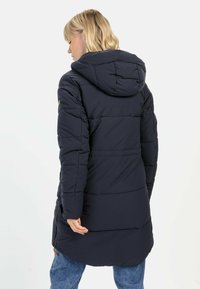 Mørkeblå puffjakke med hætte, der har vandrette syninger, sidelommer med lynlås og en afslappet pasform. Glat, isoleret stof.