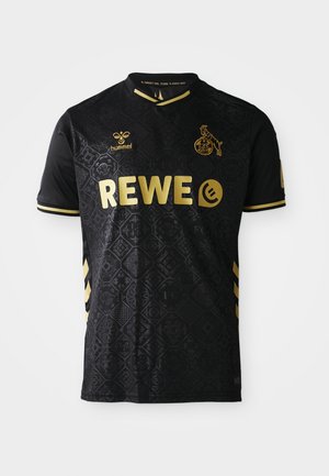 Camiseta de fútbol negra con acentos dorados, con un diseño estampado, cuello redondo y mangas cortas. Logo de "REWE" y tres rayas en las mangas.