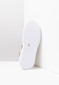 Białe sneakersy z złotą teksturowaną wstawką. Posiadają wzorzystą gumową podeszwę i znakowanie po boku. Rozmiar oznaczony jako 37.