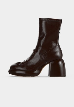 Bottine brillante marron foncé avec bout arrondi, talon bloc épais surélevé et dessus en cuir lisse cousu, vue latérale.