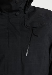 Black waterproof jacket featuring a high collar, elasticized cuffs, and a zippered chest pocket. Smooth texture with a subtle pattern.