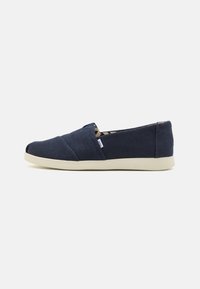 Marinede blå slip-on sko med et teksturert stoffoverdel, hvit gummisåle og designpryd med kryssøm. Minimalistisk stil med elastiske sider.