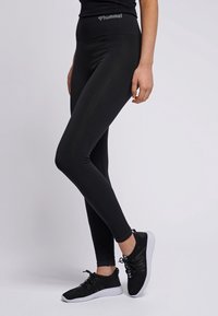 Svart träningsleggings med hög midja och ribbad textur. Kombineras med svarta och vita lätta sneakers. Logotyp på midjan.