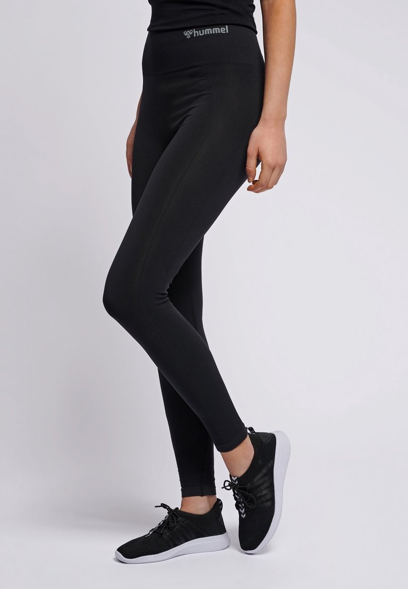 Svart träningsleggings med hög midja och ribbad textur. Kombineras med svarta och vita lätta sneakers. Logotyp på midjan.