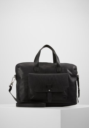 Mallette en cuir noir avec poche à rabat avant, deux poignées et bandoulière détachable, présentée sur un piédestal blanc.