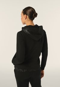 Felpa nera con cappuccio caratterizzata da un design a rilievo discreto sulla schiena e un orlo a fantasia; tessuto morbido con una vestibilità comoda.