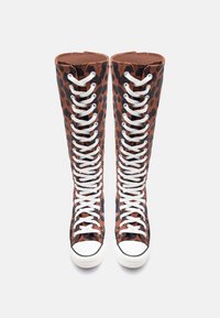 Ψηλά αθλητικά παπούτσια με λεοπάρ σχέδιο, λευκές λαστιχένιες μύτες και λευκά κορδόνια δεμένα πλήρως, απεικονιζόμενα από μπροστά σε λευκό φόντο.