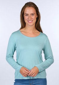 Heller blauer Langarmshirt mit rundem Ausschnitt, gerippten Saumdetails und einer glatten, weichen Textur. Kombiniert mit Jeans.