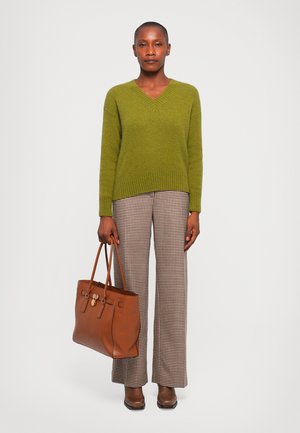 Pull vert en col en V, pantalon à carreaux marron et beige, sac en cuir marron avec quincaillerie dorée, et bottines marron.