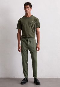Olijfgroene katoenen t-shirt met korte mouwen en een klein logo op de borst, gecombineerd met bijpassende joggers met trekkoord en zijzakken.