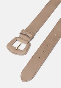 Beige nahka vyö, jossa on neliömäinen kultasävyinen solki, sileä rakenne ja useita säätöreikiä pituuden varrella, supistuva toisessa päässä.