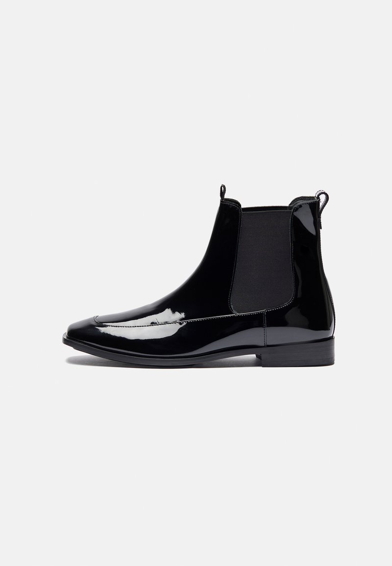 Black patent leather ankle boots with elastic side panels, pointed toe, and pull tabs for easy wear. Flat sole with minimal accent stitching.
