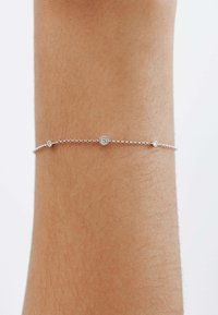 Pulsera de cadena de plata con pequeños acentos redondos brillantes, sobre un tono de piel suave, destacando el diseño y la artesanía delicados.