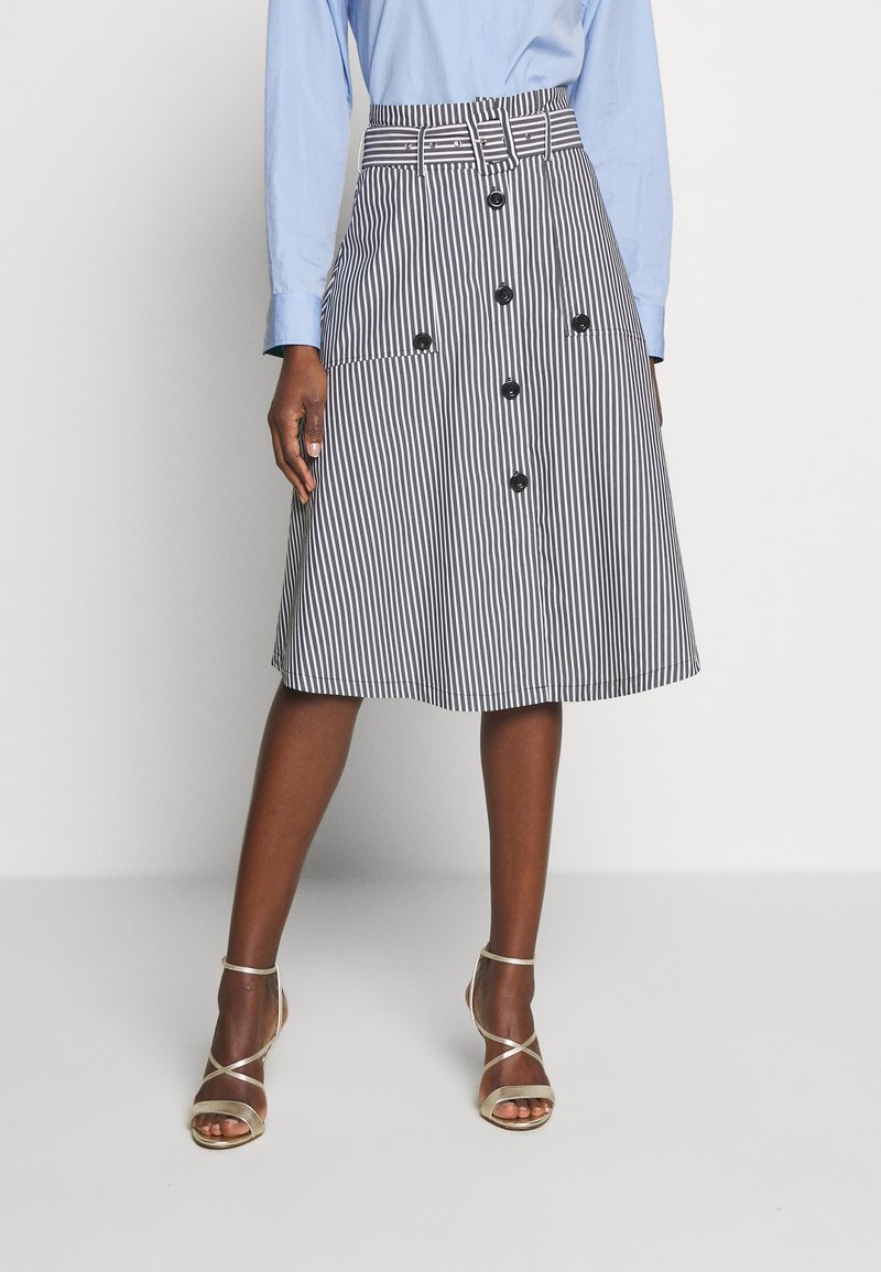 Pruhovaná sukně ke kolenům s opaskem, dvěma předními kapsami a černými knoflíky; vyrobena z lehké tkaniny v bílé a námořnické modré barvě.