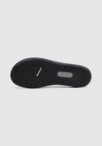 Suela de zapato de goma negra con una superficie texturizada y con patrón para mayor tracción. Presenta un logotipo central y varía en el diseño de la banda de rodadura.