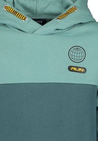 Felpa con cappuccio in teal chiaro e teal scuro. Presenta il logo del globo nero e il patch "FUN". Accenti della coulisse a disegno giallo e nero.