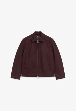 Mørkebrun lynlåstrøje med krave, lange ærmer og to forlommer, lagt fladt ud på en hvid baggrund.