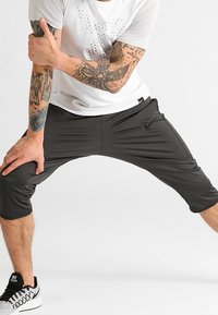 Pantalones cortos deportivos negros con un ajuste relajado, cinturilla elástica y bolsillos laterales, combinados con una camiseta blanca que presenta un diseño gráfico.