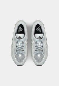 Light gray athletic shoes with a mesh upper, textured accents, black insoles, and a lace-up design. Features the Adidas logo on the tongue.
