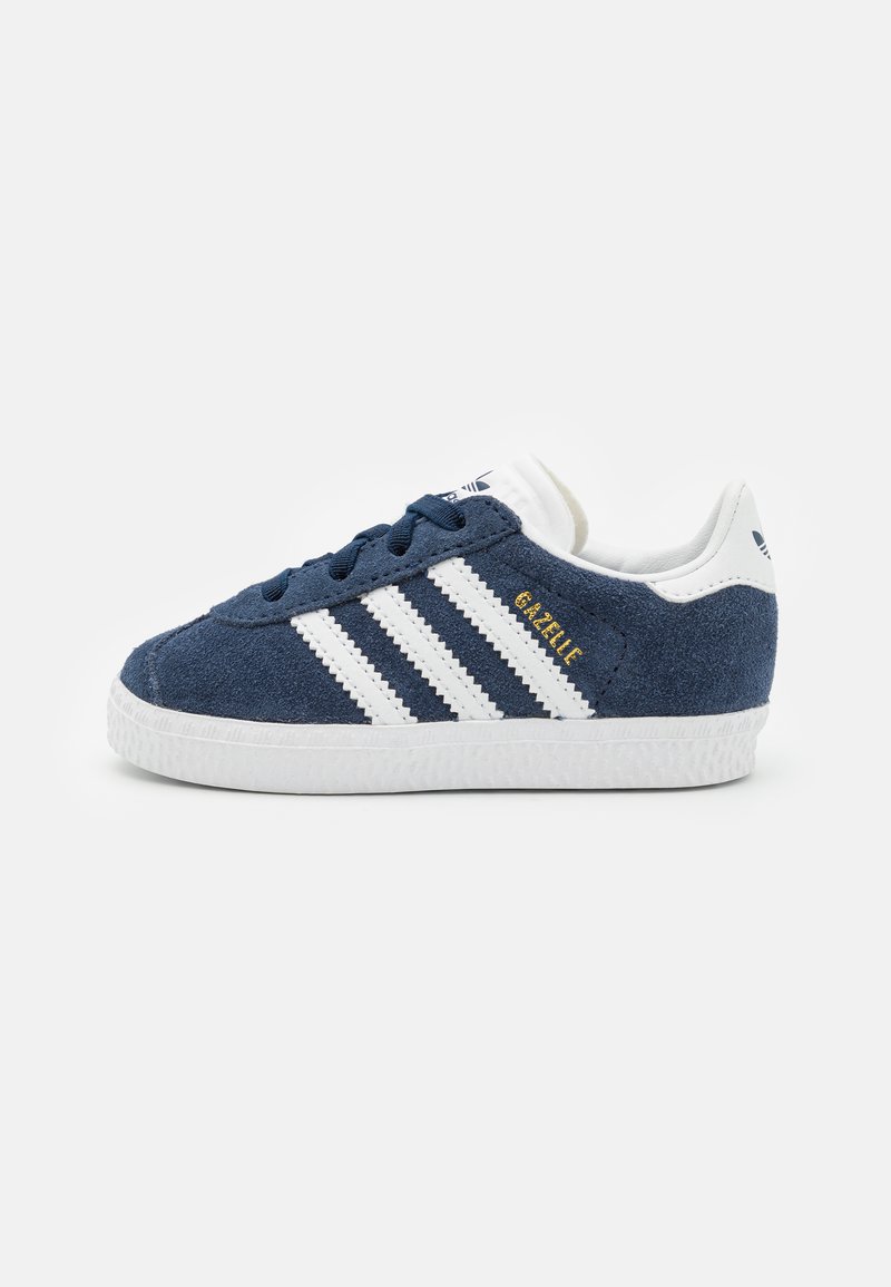 Blue suede sneaker with white rubber sole, featuring three white stripes and gold "Gazelle" branding on the side. Laced design, rounded toe.
