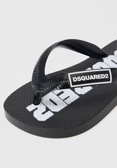 Μαύρη σαγιονάρα από καουτσούκ με υφή στη σόλα, με μαύρο λουράκι και λευκό λογότυπο «DSQUARED2» εμφανές.