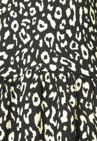 Tissu à imprimé léopard noir et blanc avec un détail de couture froncée créant des plis doux et une texture.