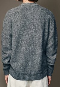 Suéter de punto gris texturizado con cuello y puños acanalados, que presenta un corte relajado y una vista trasera que resalta su patrón tejido.