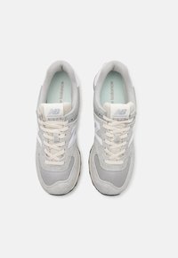 Grijze sneaker met een mix van suède en mesh materialen. Kenmerkt zich door witte branding, een vetersluiting en een gestructureerde rubberen zool.