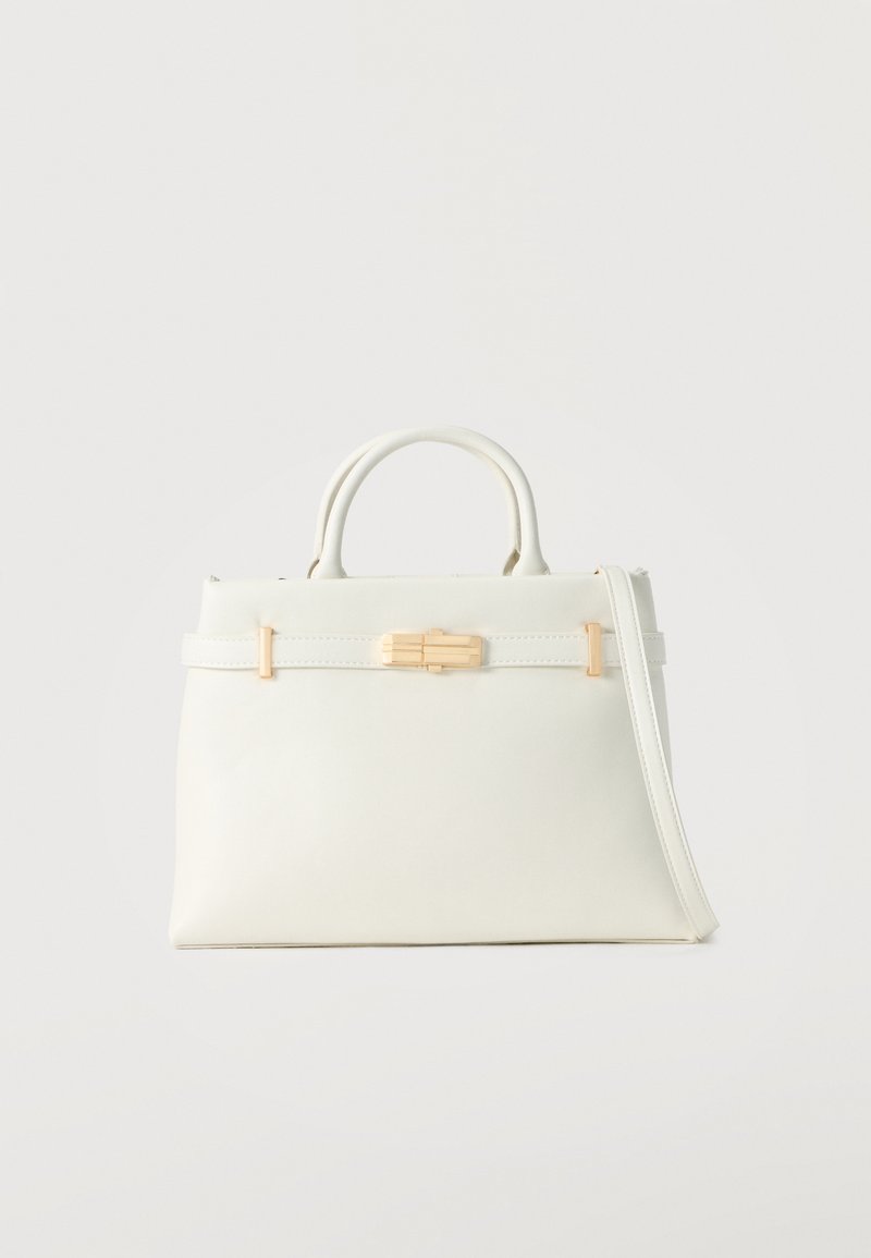 Λευκή δερμάτινη τσάντα χειρός με διπλές λαβές, μακρύ ιμάντα ώμου και κλείσιμο με χρυσό κούμπωμα σε απλό φωτεινό φόντο.