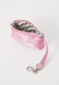 Pochette zippée en satin rose avec le logo "Juicy Couture", doublure intérieure à motifs et porte-clés en argent détachable.