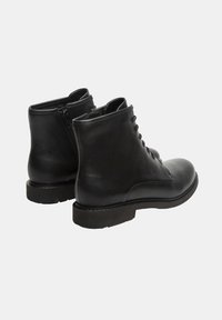 Bottines en cuir noir à bout rond, avec lacets à l'avant et fermeture éclair sur le côté. Texture lisse et coutures renforcées le long de la semelle.
