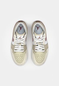 Sneakers beige e bianche con accenti grigi, punta traforata, lacci bianchi e logo iconico sulla linguetta e sui lati. Texture in pelle liscia.