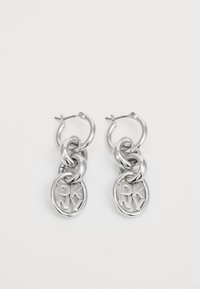 Silver hoop earrings featuring intertwined chains and circular charms with "DKNY" lettering. High-shine metal finish with smooth texture.