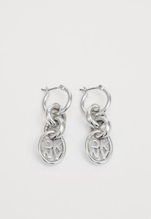 Brincos de argola prateados com correntes entrelaçadas e charmes circulares com a inscrição "DKNY". Acabamento metálico de alto brilho com textura suave.