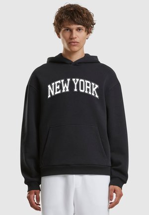Zwarte hoodie met witte "NEW YORK" tekst op de borst. Voorzien van een voorkant zak en ribgebreide boorden en onderrand. Zacht stoftextuur.