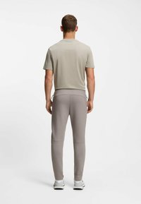 Herren-T-Shirt in Hellgrau mit kurzen Ärmeln, kombiniert mit hellgrauen, schmal zulaufenden Jogginghosen. Die Hose besteht aus Stretchstoff und hat einen Kordelzug am Bund.