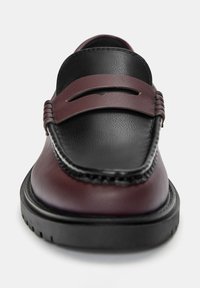 Bordeaux- og sorte læder loafers med en afrundet tå, synlige syninger og en elegant, flad gummisål. Har en dekorativ rem.