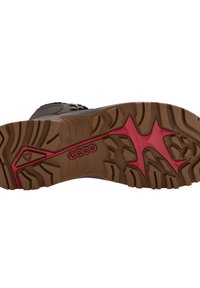 Suola di scarpa marrone con superficie in gomma testurizzata, caratterizzata da un design con accenti rossi e branding. Il motivo del battistrada migliora la trazione.