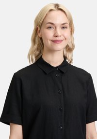 Czarna koszula krótki rękaw z teksturowanej tkaniny, z klasycznym kołnierzykiem i zapięciem na guziki z czarnymi guzikami.