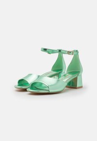 Mintgröna högklackade sandaler i slät metallisk material, med öppen tå, ankelslingor och blockklackar med en blank yta.